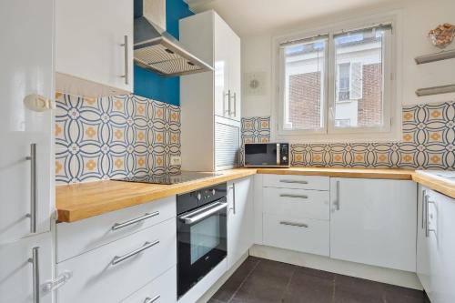une cuisine avec des armoires blanches et un micro-ondes dans l'établissement Appartement Voltaire - Welkeys, à La Garenne-Colombes