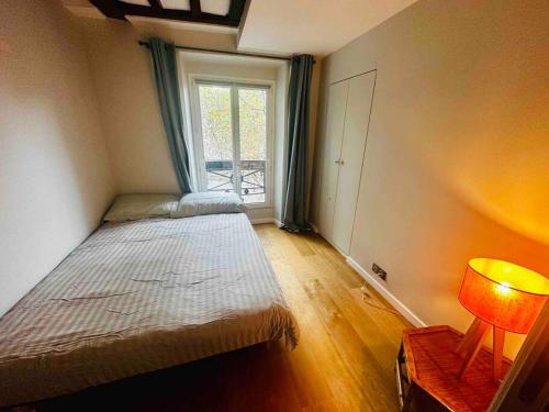 une petite chambre avec un lit et une fenêtre dans l'établissement Appartement Cosy au coeur de Paris, à Paris