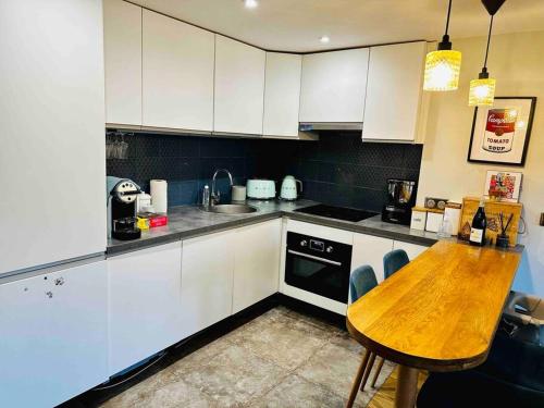une cuisine avec une table en bois et des armoires blanches dans l'établissement Appartement Cosy au coeur de Paris, à Paris