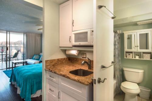 a bathroom with a sink and a toilet and a bedroom at Island Colony 4309 - 30-Night Minimum in Honolulu