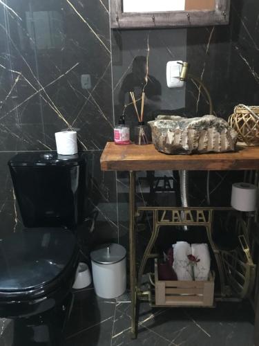 uma casa de banho com um WC preto e uma mesa de madeira em Gramado Centro 3 Hospede Loft 2 em Gramado