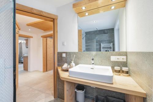 een badkamer met een witte wastafel en een spiegel bij Landhaus Plainer in Innsbruck