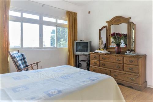 een slaapkamer met een bed, een dressoir en een spiegel bij 1940s B&B Mi casa, tu casa Roma Norte in Mexico-Stad