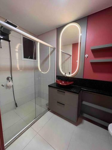 La salle de bains est pourvue d'une douche, d'un lavabo et d'un miroir. dans l'établissement Lindo e aconchegante, à Bento Gonçalves