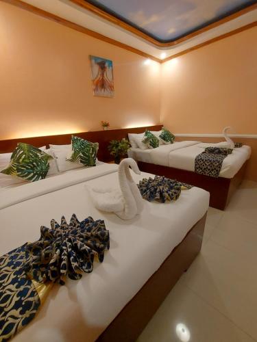Una habitación con tres camas con cisnes. en New Village Lodge, en Oslob