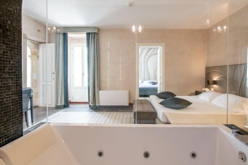 a large bathroom with a tub and a bedroom at De Stefano Palace Luxury Hotel in Ragusa