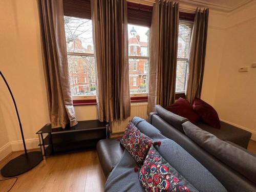 a living room with a couch and two windows at Flat espaçoso 3min do metro in London