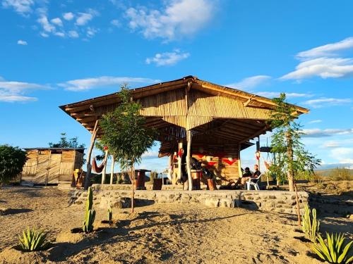 een gebouw met een houten dak op een zandveld bij Mana Star Lounge Hotel in Villavieja
