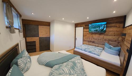 a bedroom with two beds and a tv on the wall at Appart Mona in Ramsau im Zillertal