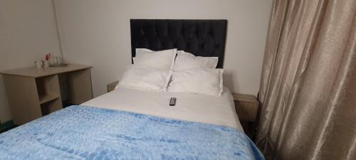 a bed with a black headboard and white pillows at Ojong's Court Bellville in Cape Town