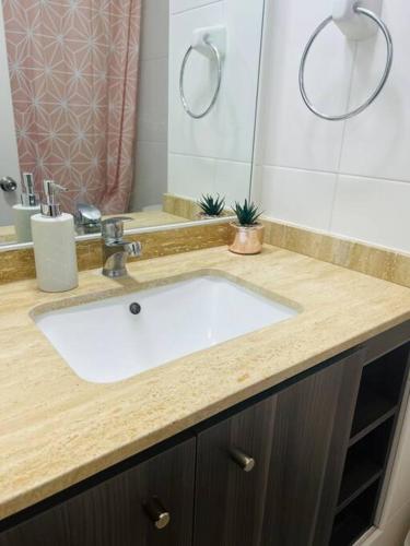 ein Badezimmer mit einem weißen Waschbecken und einem Spiegel in der Unterkunft Departamento en Iquique in Iquique