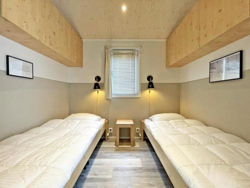 two twin beds in a room with a window at Nice chalet with garden at the Utrechtse Heuvelrug in Rhenen
