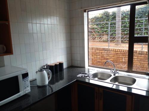 a kitchen with a sink and a window at Tshidiso Guesthouse in Centurion