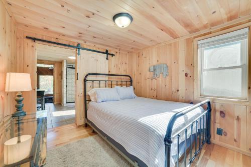 a bedroom with a bed in a room with wooden walls at Lakefront Kalkaska Cottage with Fire Pit! in Kalkaska