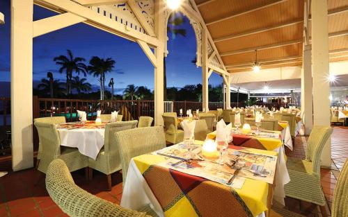 a restaurant with white tables and chairs and avisor at TI OASIS vue Mer dans village Pierre & Vacances in Sainte-Luce