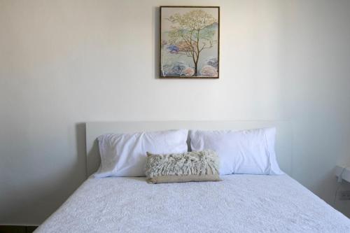uma cama com lençóis brancos e uma foto na parede em Sunset Apartment D em San Felipe de Puerto Plata