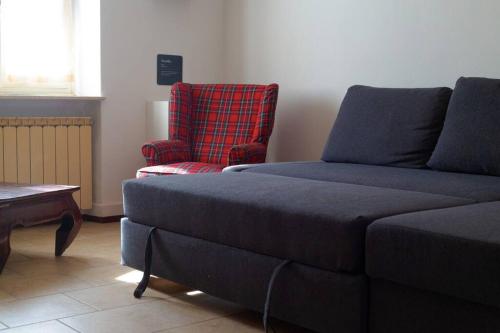 a living room with a couch and a red chair at Maria's Bed - Intero alloggio accogliente in Dorno