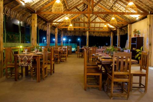 um restaurante com mesas e cadeiras de madeira e luzes em POUSADA CAJUEIRO em Santo Amaro