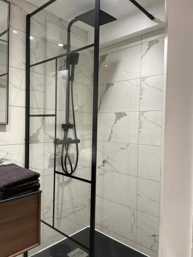 La salle de bains est pourvue d'une douche et de murs en marbre blanc. dans l'établissement MC Suite CMZ Métropolis PlaceDucale, à Charleville-Mézières