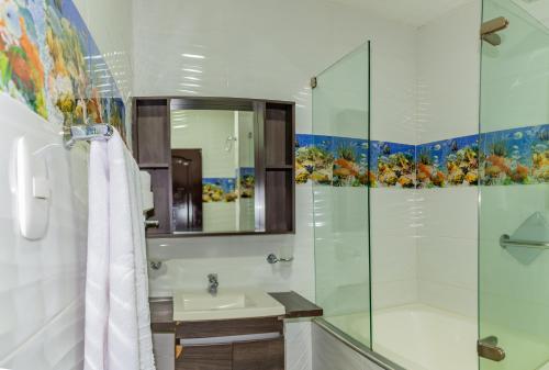 a bathroom with a shower and a sink and a mirror at Hotel Medellín Rodadero in Santa Marta