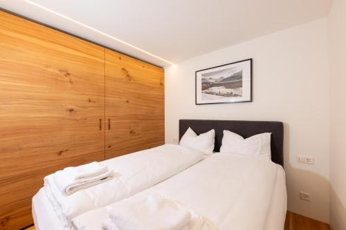 a bedroom with a large white bed with a wooden wall at New! Cozy, central apartment with a stunning view in St. Moritz