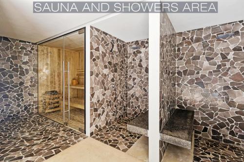 a bathroom with a shower with a stone wall at IIK Tulum Luxury Condo by Spot Rentals in Tulum