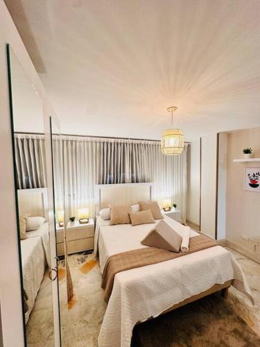 a white bedroom with a large bed and a chandelier at hermoso aparta estudio nórdico in Cali