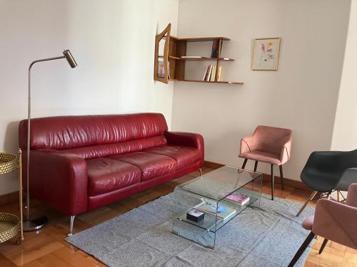 a living room with a red leather couch and a glass table at Stylish apartment dowtown 78m2 in Santiago