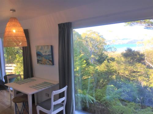 a dining room with a table and a large window at Studio 531 in Coromandel Town