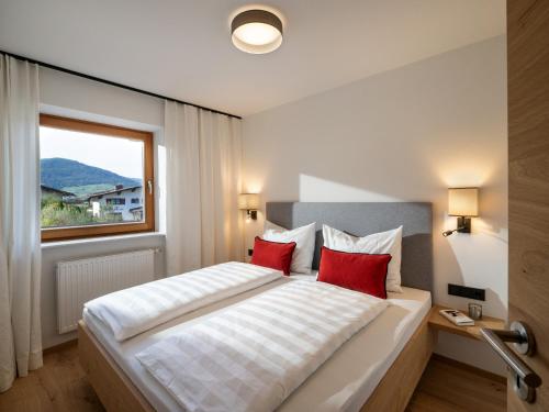 - une chambre avec un lit doté d'oreillers rouges et une fenêtre dans l'établissement Appartementhaus Schubert, à Westendorf