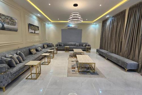 a living room with couches and tables and a screen at شالية بيهاتش in Al Madinah