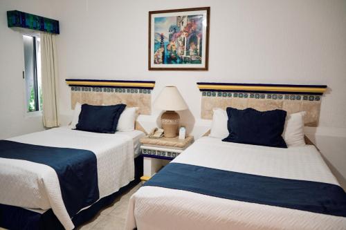 a hotel room with two beds and a window at The Inn at Mazatlan in Mazatlán