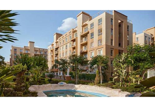 a large apartment building with a swimming pool in front of it at A Wonderful Apartment in a compound in October Gardens in ‘Ezbet `Abd el-Ḥamîd