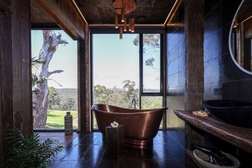a bathroom with a tub and a large window at Clifftop at Hepburn in Hepburn Springs