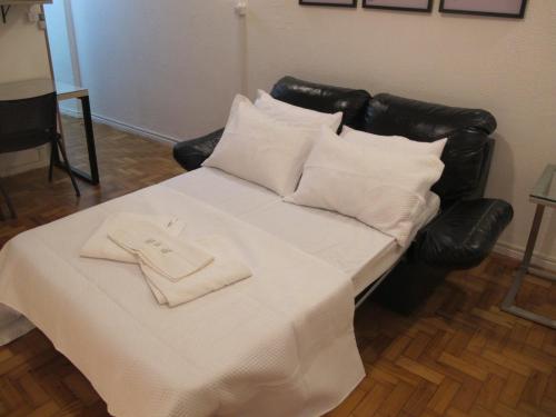 a bed with a white blanket and pillows on it at Apartamento quarto e sala in Rio de Janeiro
