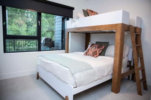 a bedroom with a bunk bed with a ladder at Le Refuge - Revelstoke Condo with Hot Tub in Revelstoke