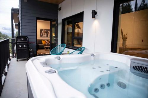 a jacuzzi tub on the balcony of a house at Le Refuge - Revelstoke Condo with Hot Tub in Revelstoke