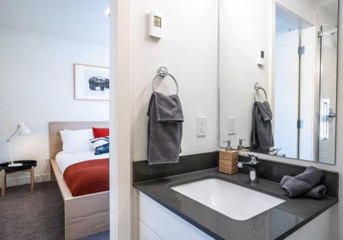 een badkamer met een wastafel en een slaapkamer met een bed bij Reved Up & Out - Remarkable Two Bedroom Condo in Revelstoke