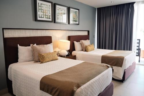 a hotel room with two beds and a window at The Inn at Mazatlan in Mazatlán