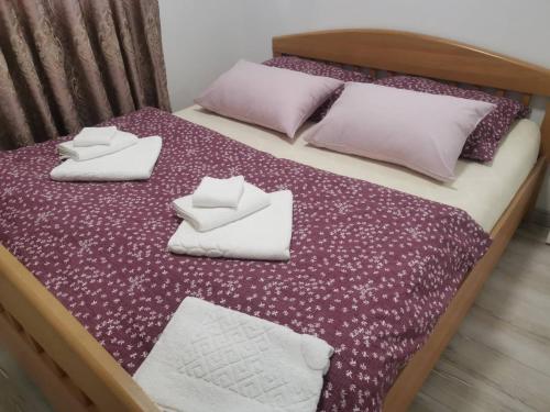 - un lit avec des oreillers violets et blancs dans l'établissement APARTMAN APOLON, à Doboj