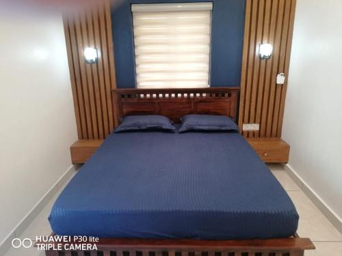 a bedroom with a blue bed with a window at Thekkumbath Sea Breeze Pool villa in Kannur