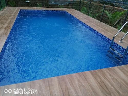 a large blue swimming pool with a wooden floor at Thekkumbath Sea Breeze Pool villa in Kannur