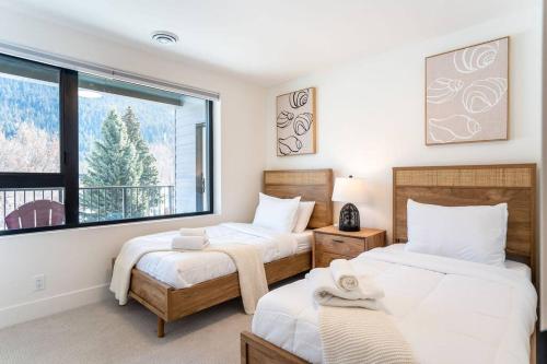 1 dormitorio con 2 camas y ventana grande en Rocky Ridge Getaway - Modern Getaway in Revelstoke, en Revelstoke