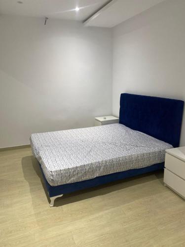 a bedroom with a blue bed in a white room at Apartment in Soukra in Tunis