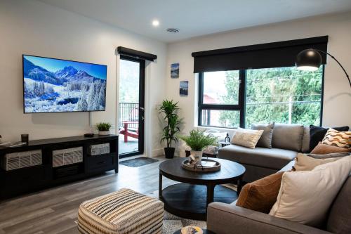 a living room with a couch and a tv at Selkirk Staytion - Stylish Condo with Hot Tub in Revelstoke