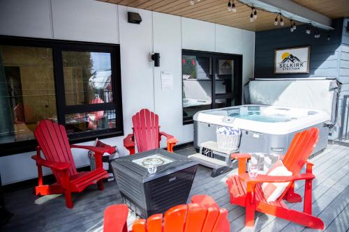 a patio with red chairs and a hot tub at Selkirk Staytion - Stylish Condo with Hot Tub in Revelstoke