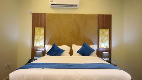 una camera da letto con un grande letto con cuscini blu e bianchi di برج بيات a Jazan