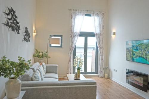 a living room with a couch and a window at Soak up the Light at a Soothing, Stylish Apartment in Swansea Marina in Swansea