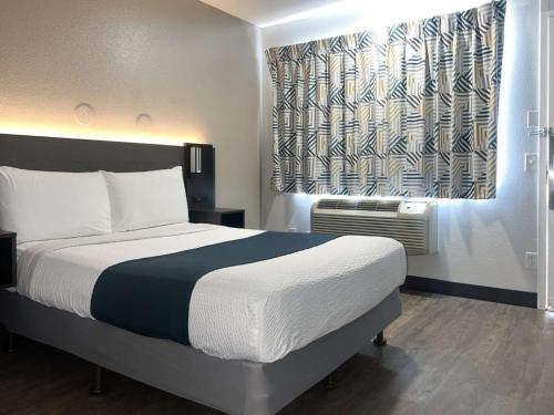 Un dormitorio con una cama grande y una ventana en Motel 6-Tulare, CA, en Tulare