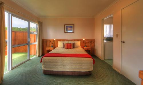 a bedroom with a bed and a large window at Islander Lodge Apartments in Burnt Pine